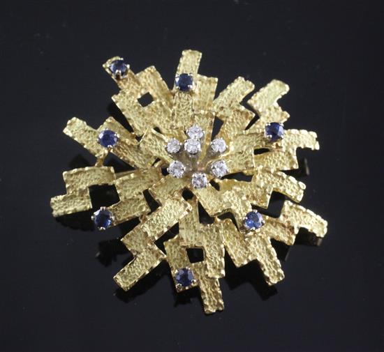 A 1970s? textured 18ct gold, diamond and sapphire set stylised starburst brooch, 43mm.